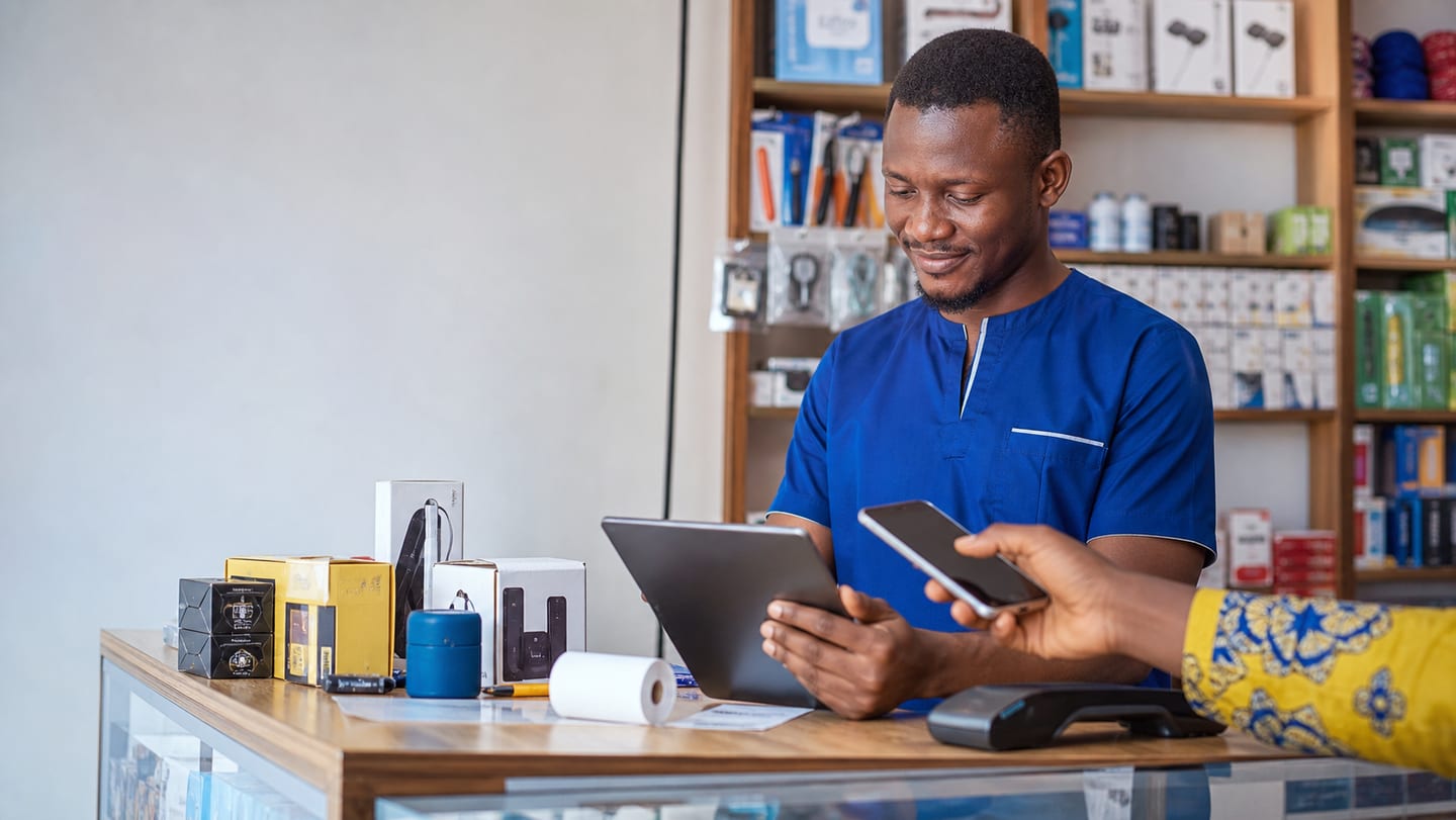 Vendeur en boutique enregistrant une vente sur tablette